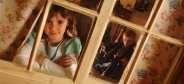 Little girl and boy looking out of cob cotage window